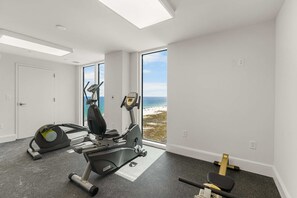 A gym with cardio equipment, a rowing machine, and a bench. - Gulf front condo with pool, beach access, and wrap around balcony (Orange Beach)