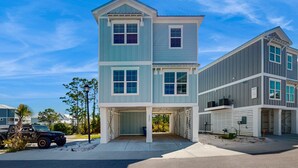A two-story building with a covered garage and a separate building attached to it. - Brilliant beach house located walking distance to beach with community pool (Orange Beach)