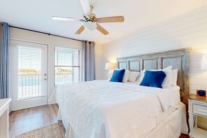 A bedroom with a bed, ceiling fan, and a view of the outside. - Waterfront, gulf view condo by beach with pool, dock & balcony (Orange Beach)
