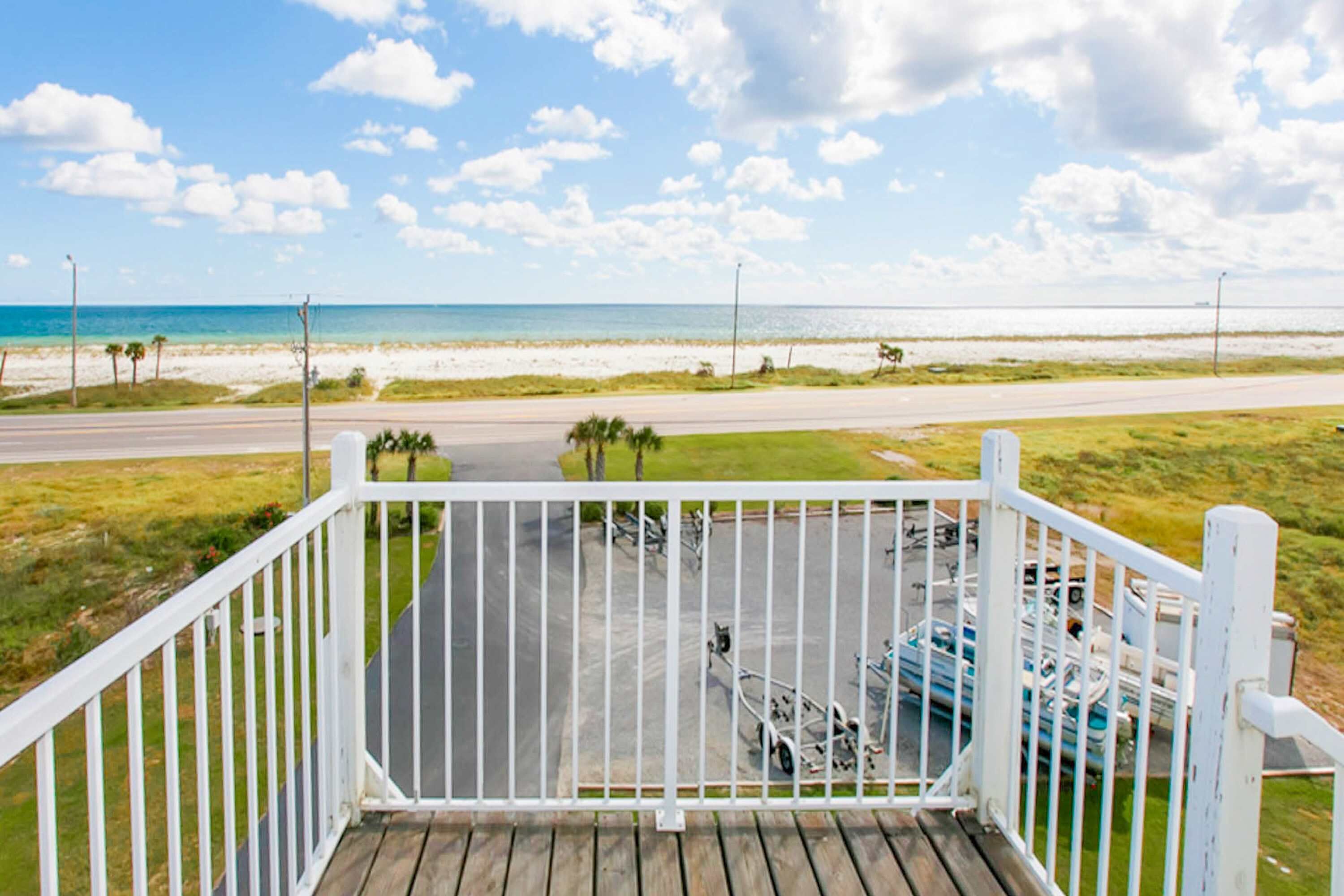 Vue depuis un balcon donnant sur une plage, avec un parking au premier plan.