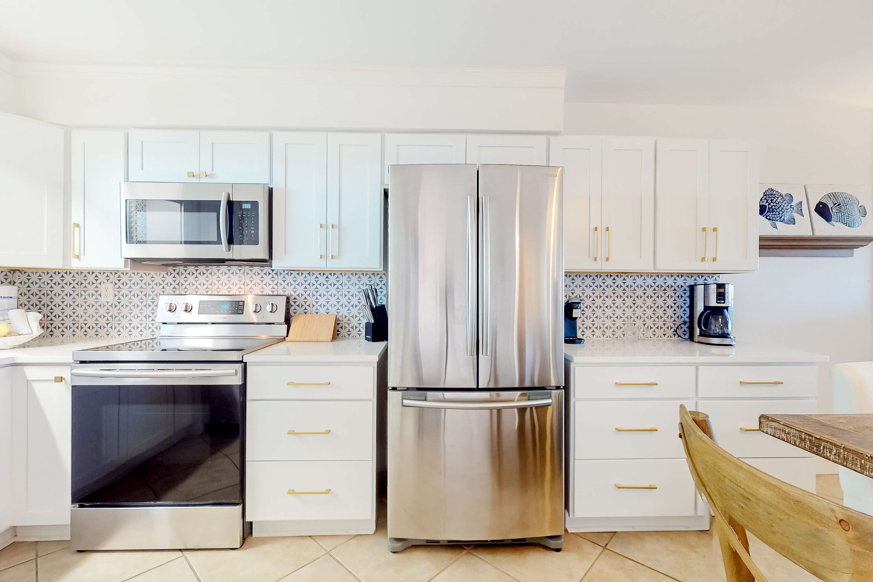 A modern kitchen with stainless steel appliances, white cabinetry, and a wooden dining table.