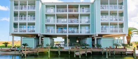 A multi-story hotel with balconies, a dock, and water in front.