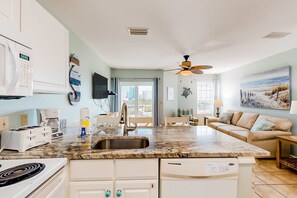 A modern kitchen with a built-in dishwasher, a coffee maker, and a toaster. - Gulf view condo with pool & fitness center - balcony, open layout, and W/D (Orange Beach)