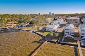 An aerial view of a coastal residential area with houses, a dock, and a clear sky. - Ground-floor condo with waterfront pool, private patio, AC, & W/D (Orange Beach)
