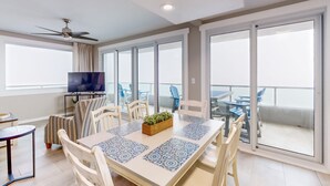 Una sala moderna con comedor, televisor y balcón con mobiliario de exterior.