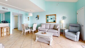 Un salon comprenant un canapé, un fauteuil, une table basse et un coin repas avec des chaises et une table.