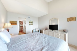 Une chambre à coucher avec un lit, une télévision, une commode et une chaise.