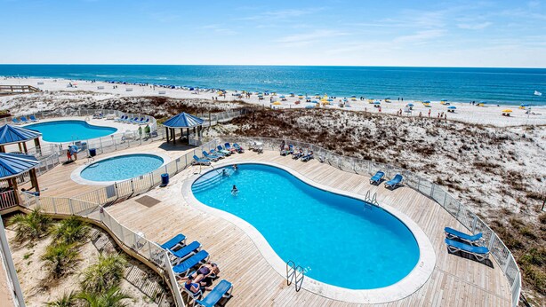 Un complexe hôtelier de bord de mer doté de plusieurs piscines, de chaises longues et de parasols.