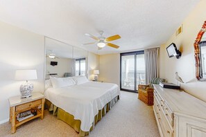 A hotel room with a bed, a ceiling fan, a TV, a dresser, a mirror, and a balcony with a view. - Beachfront Views Beside Perdido Pass (Orange Beach)