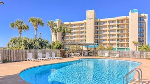 Ein Hotel mit Schwimmbad, Palmen und blauem Himmel.