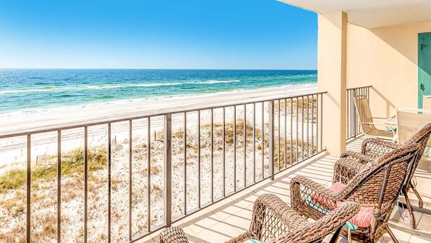 Ein Balkon mit Korbmöbeln und Blick auf einen Strand.
