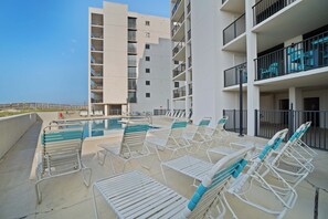 A poolside area with lounge chairs and a building with multiple balconies. - Beautiful resort condo at the foot of the beach with pool, WiFi, central AC (Orange Beach)
