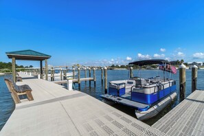 A dock with a boat, a covered seating area, and a clear view of the water. - Beautiful resort condo at the foot of the beach with pool, WiFi, central AC (Orange Beach)