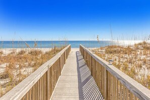 A wooden boardwalk leading to a beach with clear skies. - Beautiful resort condo at the foot of the beach with pool, WiFi, central AC (Orange Beach)