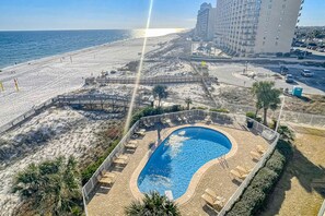 A resort with a swimming pool, beach access, and a high-rise building in the background. - Seaside escape with balcony, WiFi, pools, tennis, steam room, & gym (Orange Beach)