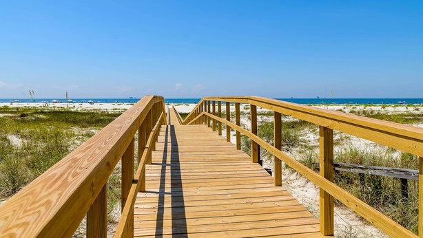 A wooden boardwalk leading to a beach with sand dunes and a clear blue sky. - Newly renovated second-floor condo with shared pool, WiFi, W/D, & central AC (Dauphin Island)