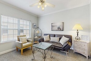 Ein Wohnzimmer mit Glastisch, Ledersofa und Bücherregal.