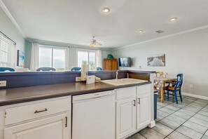 Eine Küche mit Geschirrspüler, Spüle, Deckenventilator und Essbereich mit Stühlen.