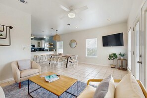A spacious living area with a dining table, sofas, and a TV mounted on the wall. - Spacious private home with patio, balconies, close to beaches (Gulf Shores)