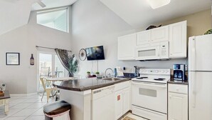 Eine moderne Küche mit weißen Schränken, einer eingebauten Mikrowelle, einem Herd und einem Kühlschrank.