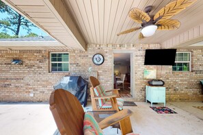 A covered patio with a brick wall, a ceiling fan, a clock, and outdoor furniture. - Seven Rings, Dog-friendly house with back patio, grill, streaming, washer,dryer (Dauphin Island)