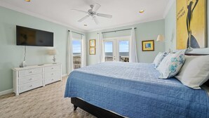 A bedroom with a bed, ceiling fan, TV, dresser, and a view of the ocean. - Gulf front home with private dune walk over, internet, & washer & dryer (Dauphin Island)