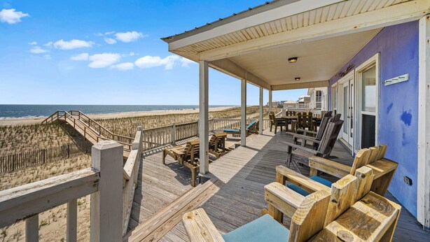 A wooden deck with outdoor furniture overlooking a beach. - Gulf front home with private dune walk over, internet, & washer & dryer (Dauphin Island)