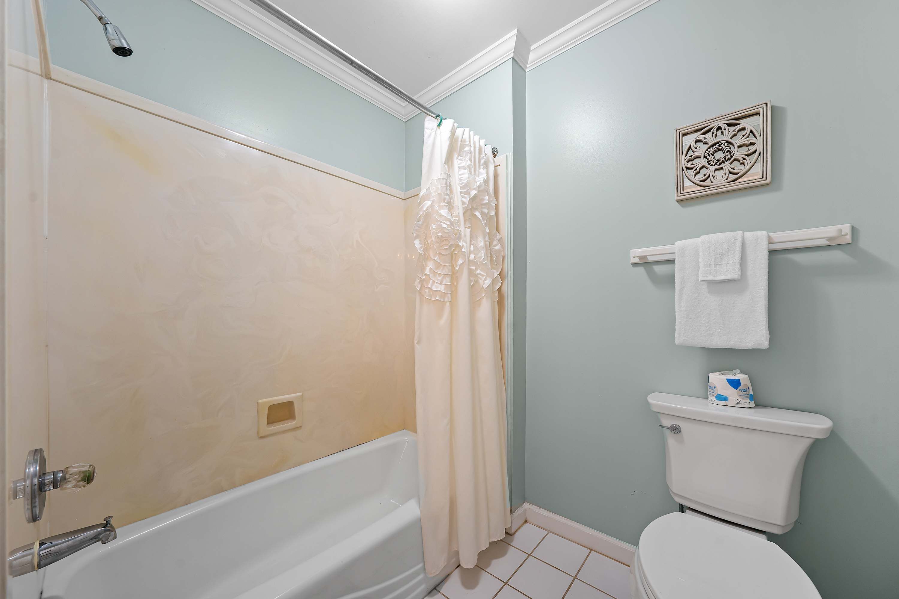 A bathroom with a bathtub, toilet, and shower curtain.