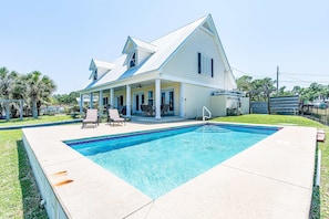 A house with a swimming pool, a covered porch, and a fenced yard. - Bayfront beauty with a pool, grill, dock, reading room, board games, & AC (Dauphin Island)