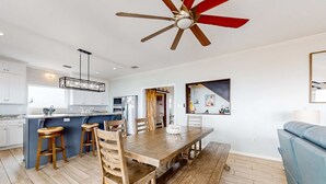 Cozinha espaçosa com banquetas de madeira, mesa de jantar e ventilador de teto.