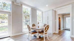 A dining area with a round table, chairs, and a view of the outdoors.