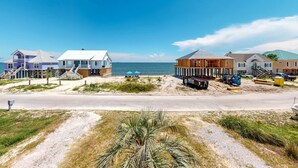 Une zone côtière avec des maisons, une plage de sable et un ciel bleu dégagé.