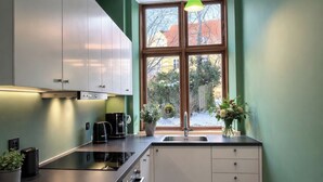 Una cucina moderna con mobili bianchi, un piano di lavoro nero e una lampada a sospensione verde.