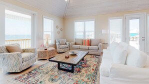 A spacious living room with a ceiling fan, large windows, and a view of the ocean. - Beautiful beach house with Gulf views, covered deck, central AC, and free WiFi (Dauphin Island)