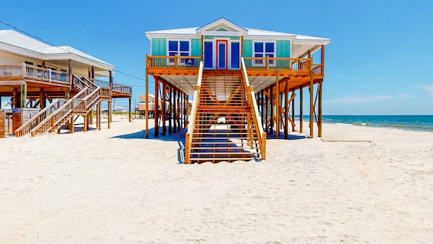 A beachfront house with a wooden staircase leading to a balcony, a pool, and a beach view. - Beautiful beach house with Gulf views, covered deck, central AC, and free WiFi (Dauphin Island)