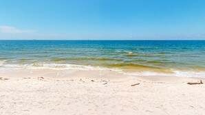 A beach with clear blue water and a sandy shore. - Beautiful beach house with Gulf views, covered deck, central AC, and free WiFi (Dauphin Island)