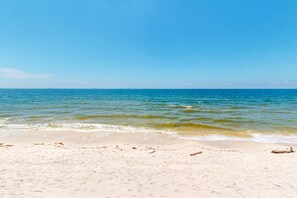 A beach with clear blue water and a sandy shore.
