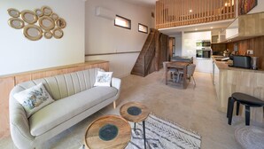 Un vaste espace de vie comprenant un canapé, une table basse et un escalier menant à un niveau supérieur.