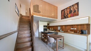 Une cuisine moderne avec un escalier en bois, un coin repas et un îlot central.