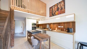 Une cuisine moderne avec une table et des chaises en bois, un four encastré et une machine à café.