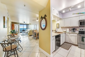 A dining area with a round table and chairs, a ceiling fan, and a view through the glass door. - Gulf-front 6th-floor condo with balcony, pool, hot tub, & sauna - beach access (Orange Beach)