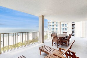 A balcony with a table and chairs, overlooking a beach and ocean. - Gulf-Front Beach Condo w/Balcony, Shared Pool, Hot Tub, A/C, Views, & Gym (Orange Beach)
