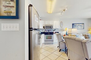 Eine Küche mit weißen Schränken, einer Mikrowelle, einem Backofen und einem Kühlschrank.