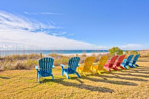 Eine Reihe bunter Adirondack-Stühle mit Blick auf einen Strand und einen klaren Himmel.