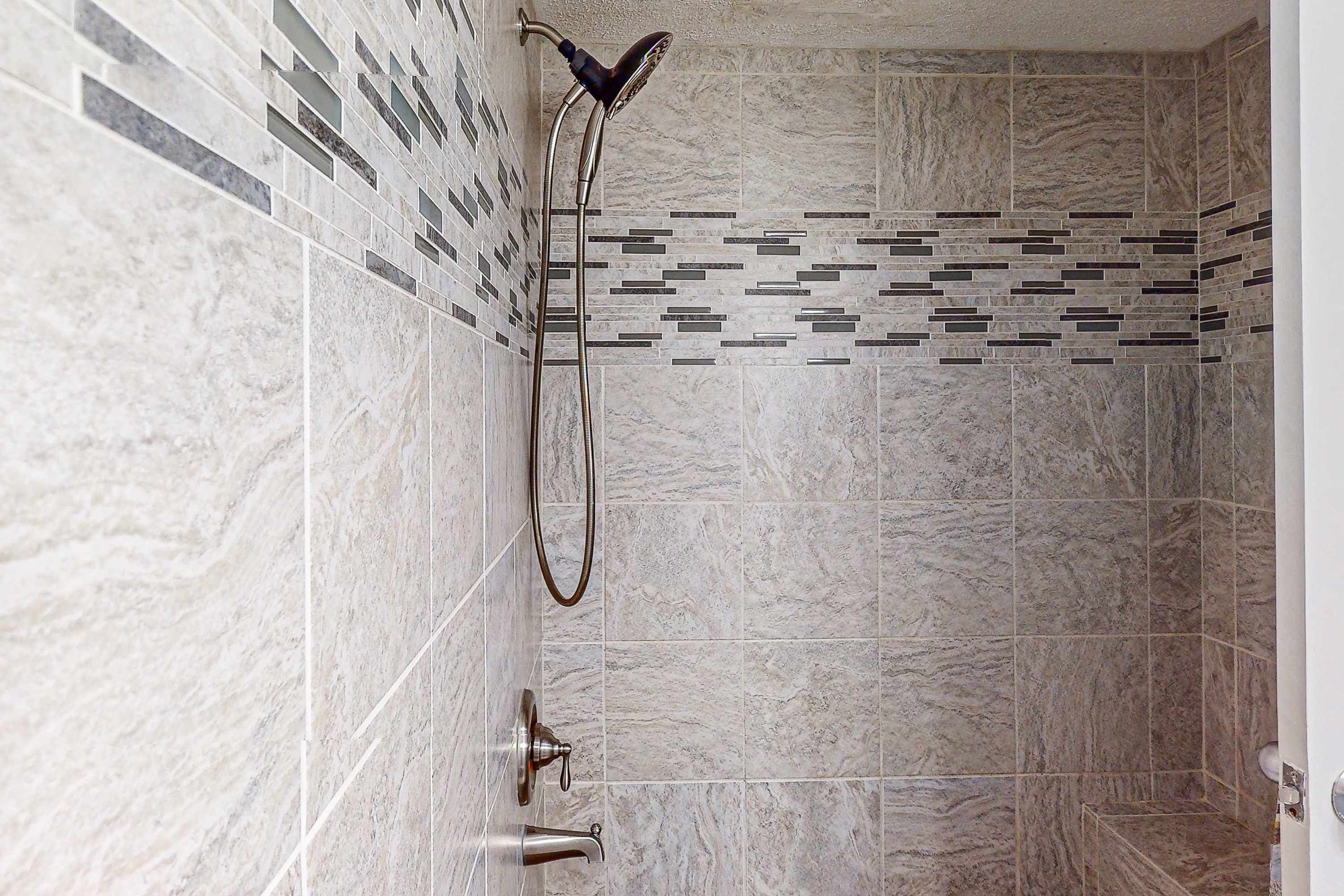 A shower with a handheld showerhead and a wall-mounted faucet.