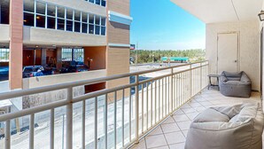 Un balcone con ringhiera, una poltrona sacco grigia e vista su un parcheggio e un edificio.