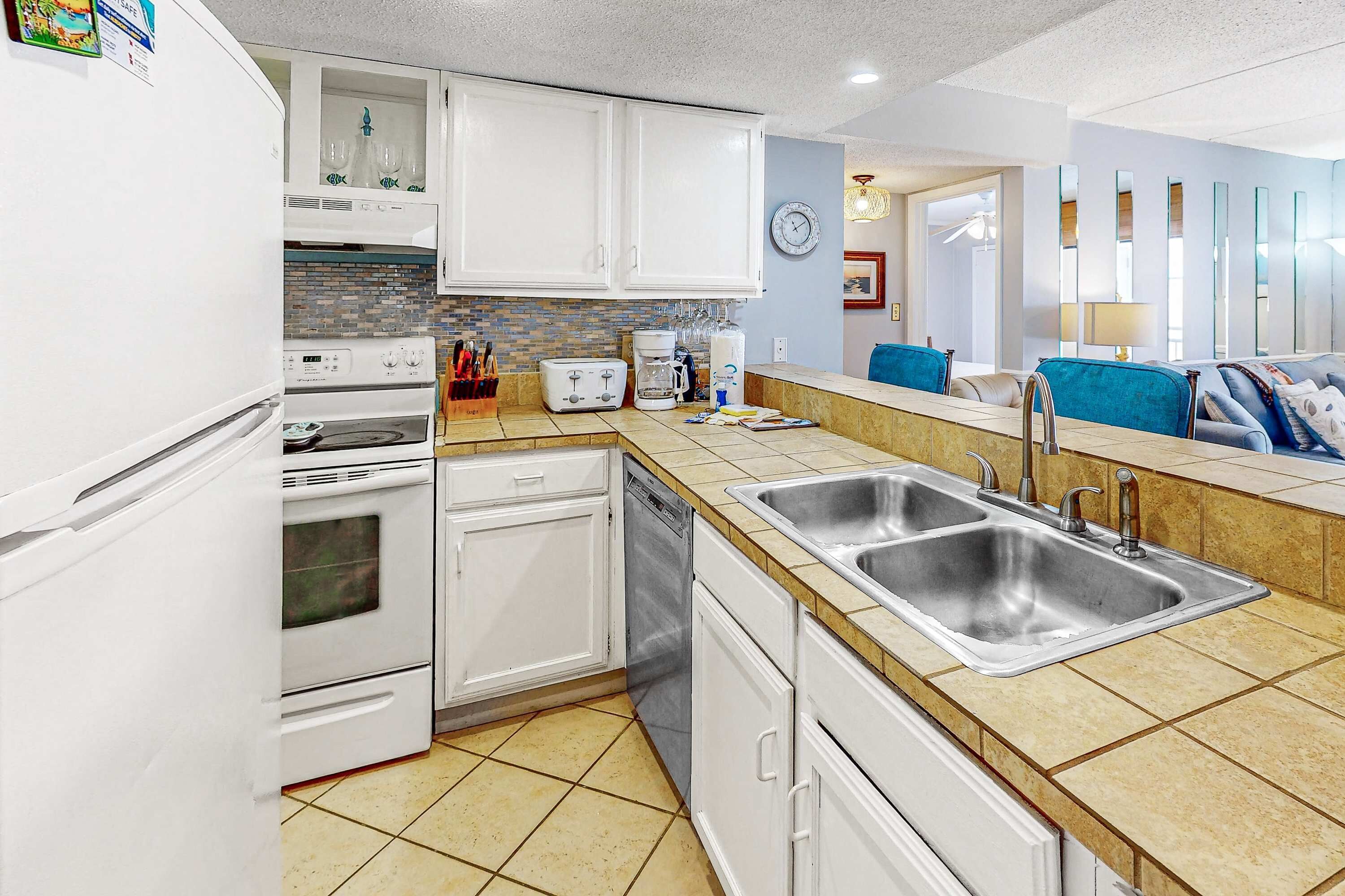 A modern kitchen with white cabinets, a double sink, a dishwasher, and a built-in oven.