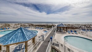 Un resort in riva al mare con diverse piscine, lettini e padiglioni.