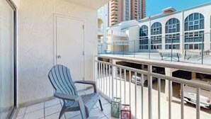 A balcony with a chair, a railing, and a view of high-rise buildings. - Updated studio w/shared outdoor pools and tennis court, family-friendly, & more! (Orange Beach)