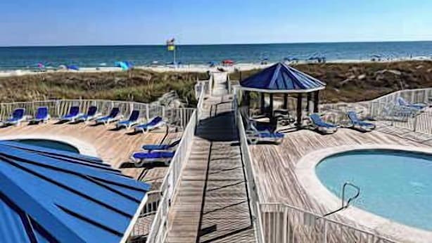 A pool area with lounge chairs and a gazebo. - Updated studio w/shared outdoor pools and tennis court, family-friendly, & more! (Orange Beach)